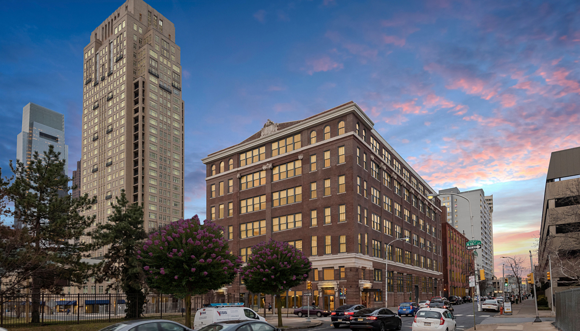 Historic brick building with large windows in an urban setting at sunset.