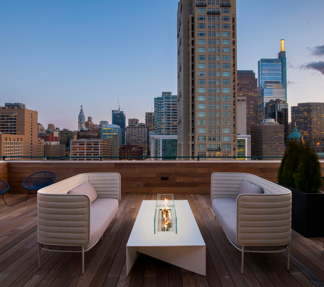 Rooftop terrace with outdoor seating and fire table overlooking the Philadelphia skyline.
