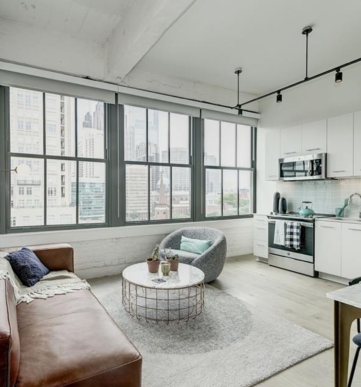 Modern apartment living area with large city-view windows and an open kitchen.