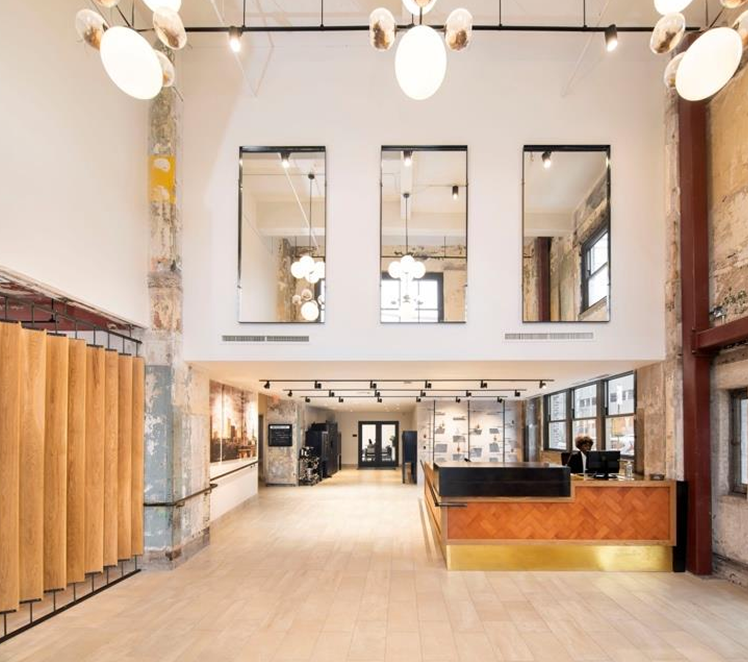 Modern lobby with a reception desk, exposed architectural details, large mirrors, and contemporary lighting.